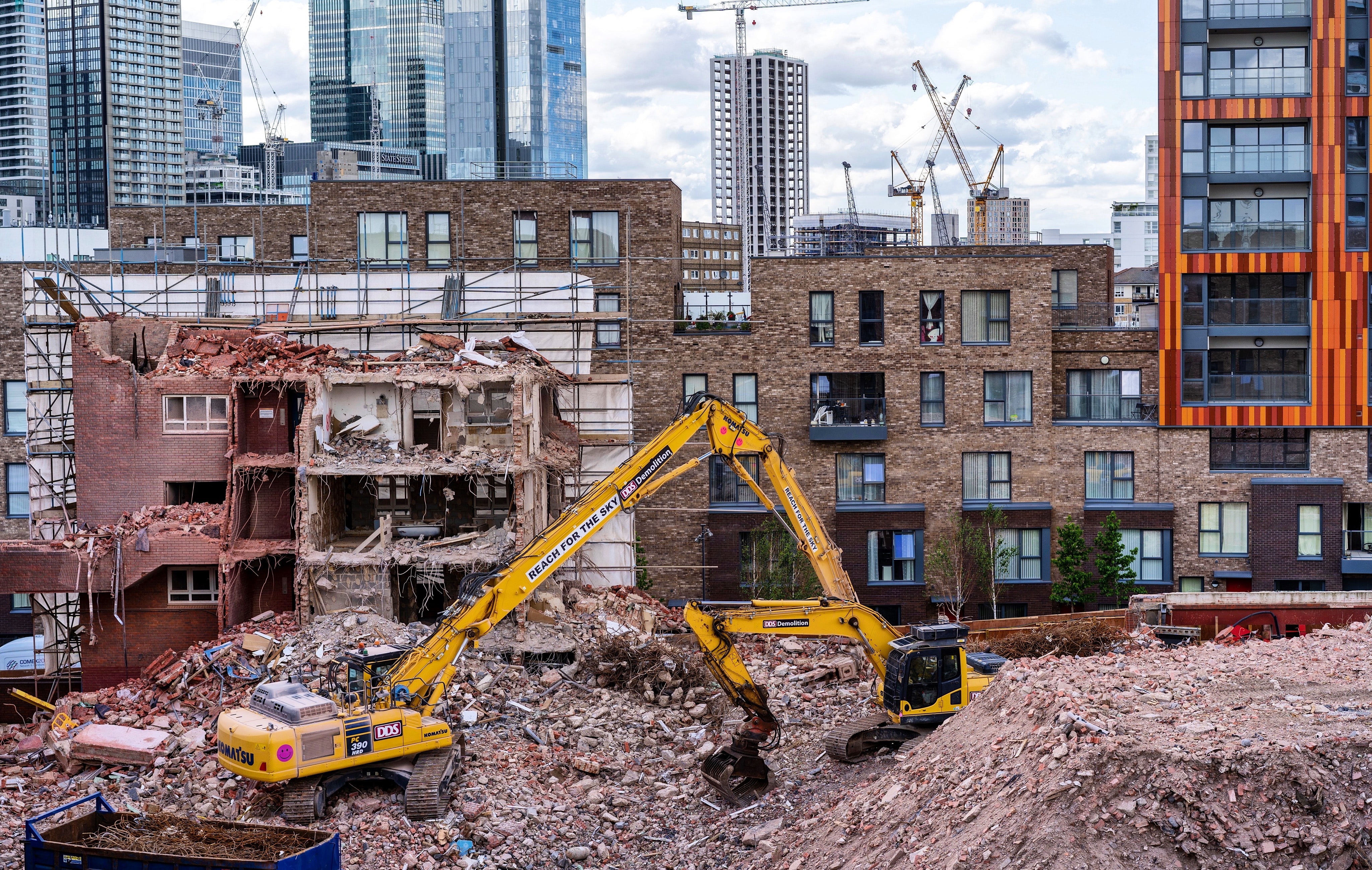 A digger on an urban construction site featuring new homes and high-rise buildings